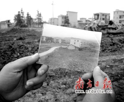 曹再发的妻子拿着房子被拆迁前的照片,站在被夷为平地的家上。南方日报记者 肖雄 摄
