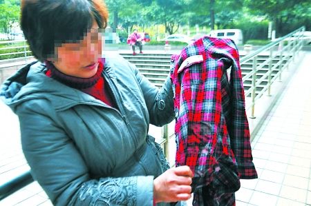 雷小丽的母亲在展示女儿被刺时穿的衣服 记者 蒋雨龙 摄
